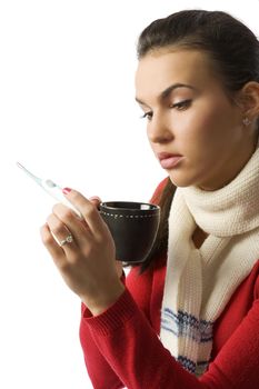 Closeup portrait of young ill woman checking her body temperature and drinking a cup of tea