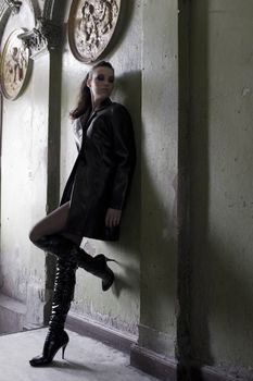 dark model wearing a leather coat and boots in an old fashion main entrance of old house