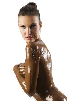 amazing shot of a young beautiful brunette with her naked body covered of sweet cream chocolate