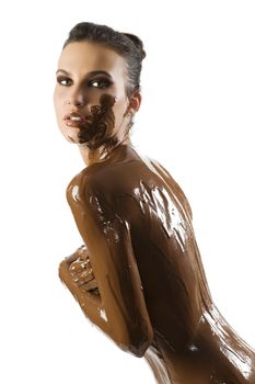 amazing shot of a young beautiful brunette with her naked body covered of sweet cream chocolate