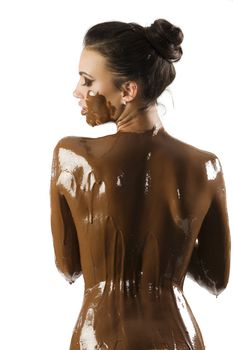 amazing shot of a young beautiful brunette with her naked body covered of sweet cream chocolate