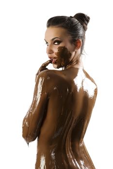 amazing shot of a young beautiful brunette with her naked body covered of sweet cream chocolate