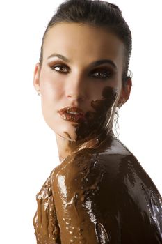 amazing shot of a young beautiful brunette with her naked body covered of sweet cream chocolate