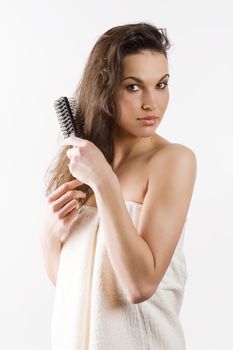 beauty shot of a young girl with a white bathrobe brushing her long wet hair