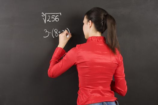 pretty young college student writing on the chalkboard/blackboard during a math class