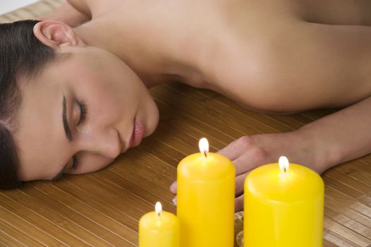 attractive beautiful caucasian woman lying down on a massage bed at a spa with candle