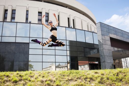 young cute modern dancer woman jumping outside near a modern building