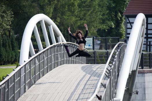 young modern dancer jumping outdoor on a white bridge