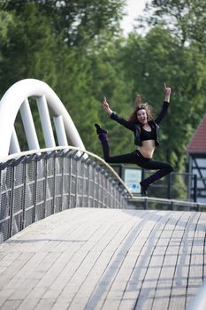 young and happy pretty woman jumping for joy on a white bridge outdoor