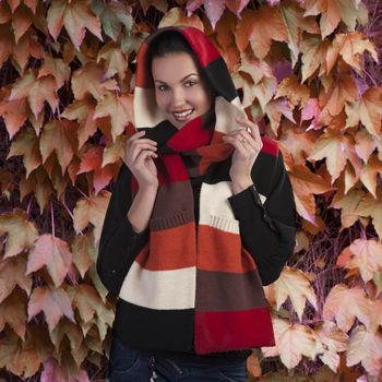 Autumn shot of a young beautiful brunette wearing a dark sweater and a fall color long scarf