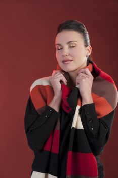 Autumn shot of a young pretty brunette wearing a dark sweater and a fall color long scarf