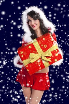 pretty brunette wearing a red santa claus dress with hood and white fur over dark blue in snow