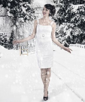 Pretty brunette with hair style and a white dress between christmas ball playing and smiling
