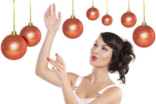 Pretty brunette with hair style and a white dress between christmas ball playing in joyful mood