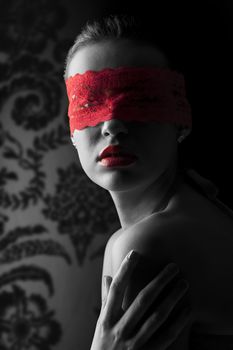 sensual portrait of a young brunette on black background with a red mask of lace