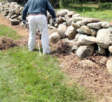 Volunteer male roadside worker clearing grass and weeds along the highway on the weekend.