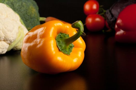 pepper on black with different vegetables in the background