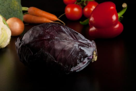 red cabbage on black with different vegetables in the background