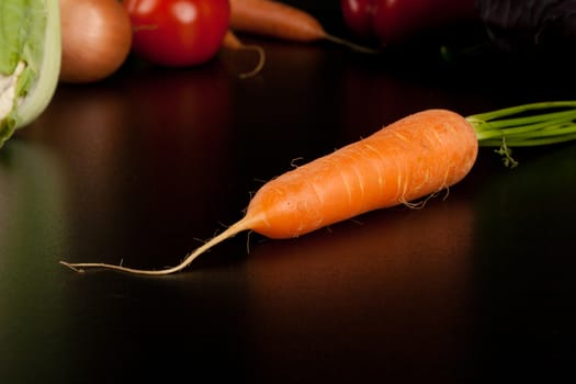 carrot on black with different vegetables in the background