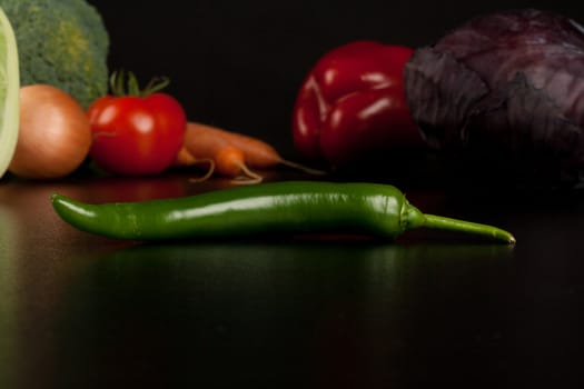 hot pepper on black with different vegetables in the background