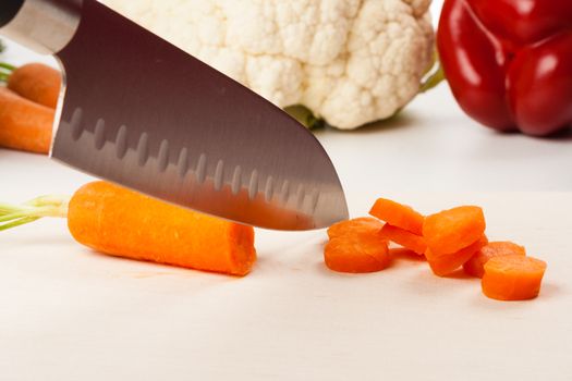 Carrot on cutting board with different vegetables in the background