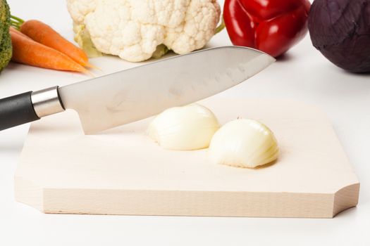 onion on cutting board with different vegetables in the background