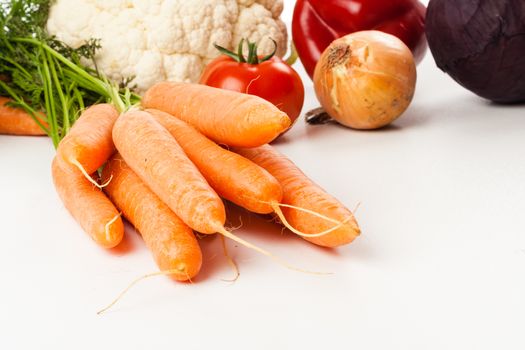 carrots on white with different vegetables in the background