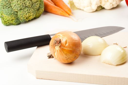 onion on cutting board with different vegetables in the background