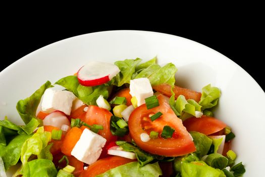 vegetable salad in white bowl on black background