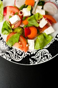 vegetable salad in stylish balck and white plate on black background