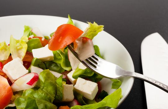 vegetable salad close up on a fork with dark background