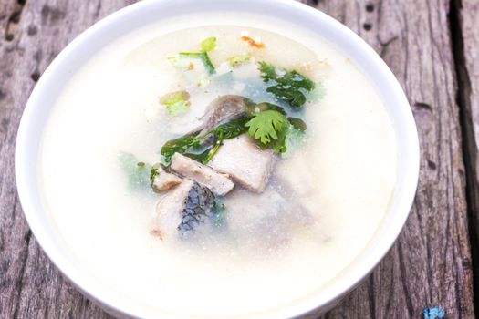 bowl of fish and wild rice soup with vegetables on wood table