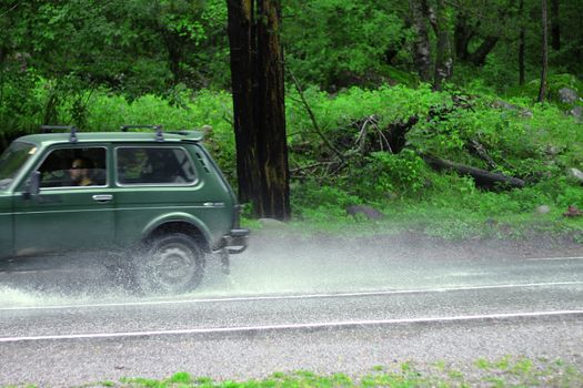 Automobile driving on the puddle on a highway