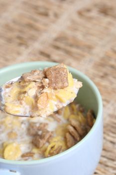 Crunchy breakfast cereals  in a blue bowl with a spoon .