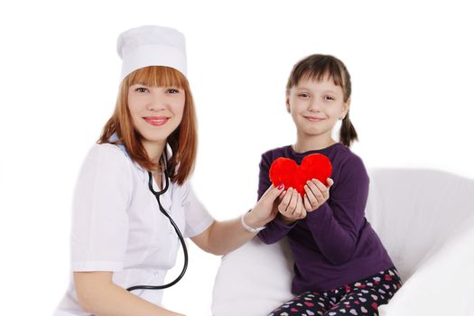 Female doctor and little girl holding plush heart over white