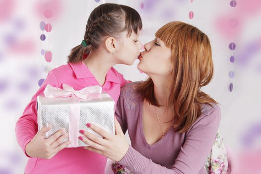 Mother and daughter kissing and holding present, pink decoration