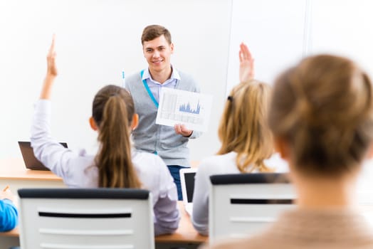 young teacher man talking with students in the classroom