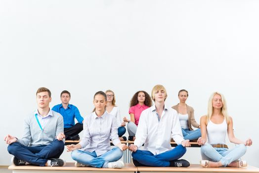 group of young people meditating in office at desk, group meditation