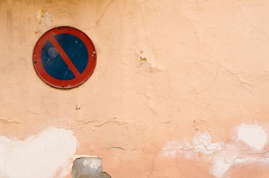 Old peeling wall with a no parking sign on it