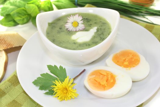 green herbs soup with eggs and a dollop of cream