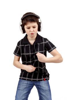 Portrait of a happy young boy listening to music on headphones and dancing against white background 