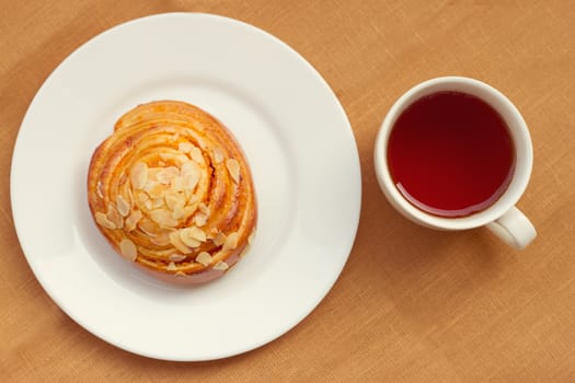 A bun and cup of tea on tray