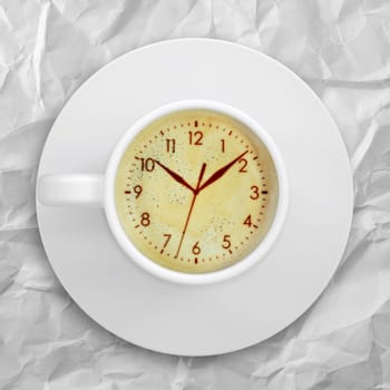 Cup of coffee standing on a crumpled paper. Picture of the clock face in the coffee crema. top view