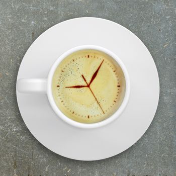 Cup of coffee standing on a abstract surface. Picture of the clock face in the coffee crema. top view