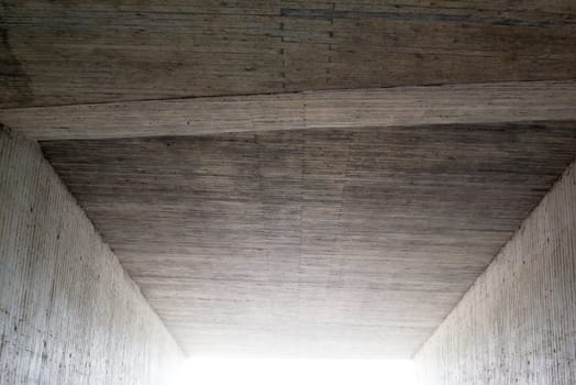 Abstract: Inside a concrete tunnel with light coming in from the exit or entrance.