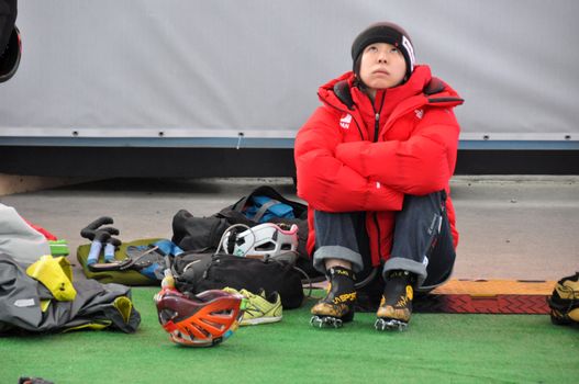 Asian woman looks up having rest ice climbing, Russia