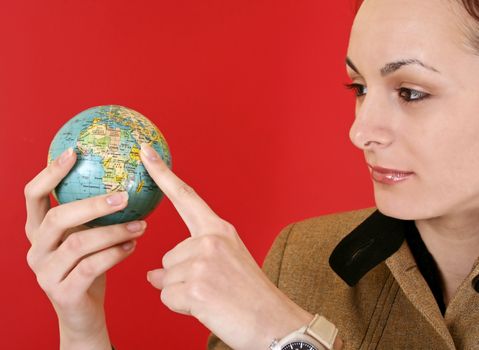 Globe in a girl's hands. Isolated on red