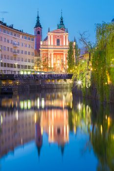 Romantic medieval Ljubljana's city center, capital of Slovenia, Europe. Night life on the banks of river Ljubljanica where many bars and restaurants take place. Franciscan Church in background