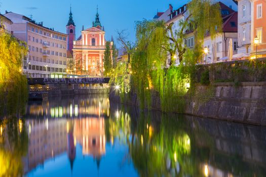Romantic medieval Ljubljana's city center, capital of Slovenia, Europe. Night life on the banks of river Ljubljanica where many bars and restaurants take place. Franciscan Church in background
