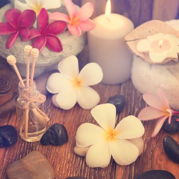 Spa treatment setting with frangipani ,pure essential oil and burning candle, vintage toned style.